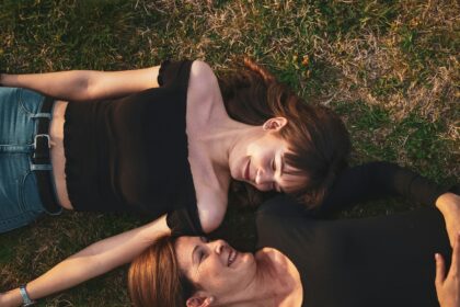 woman in black sleeveless dress lying on green grass field