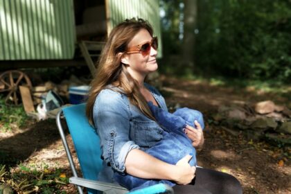 woman carrying baby while sitting on chair