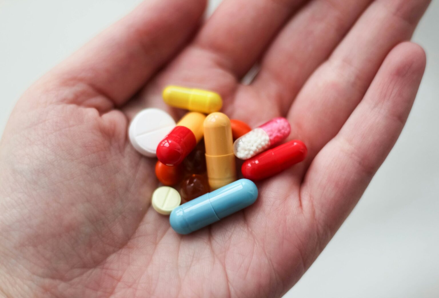 orange and white medication pill on persons hand