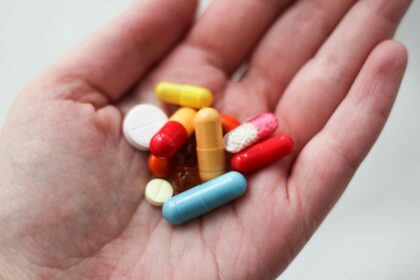 orange and white medication pill on persons hand